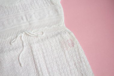 Pembe bir arka plan üzerinde beyaz bebek örgü elbise.