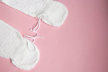 Pembe bir arka plan üzerinde beyaz bebek örgü elbise.