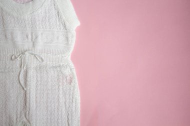 Pembe bir arka plan üzerinde beyaz bebek örgü elbise.