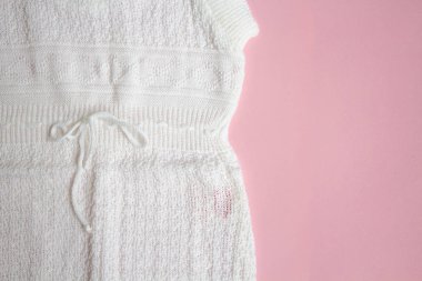 Pembe bir arka plan üzerinde beyaz bebek örgü elbise.