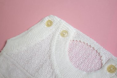 Pembe bir arka plan üzerinde beyaz bebek örgü elbise.