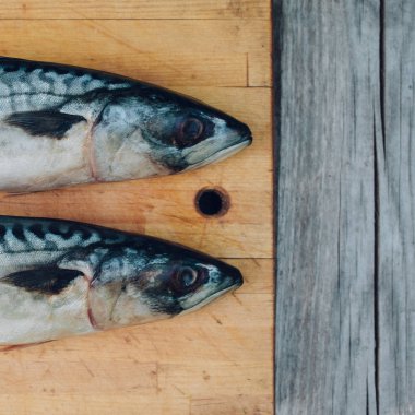bir kesme tahtası, pişirme uskumru, üzerinde iki taze balık balık kuyrukları yakın çekim