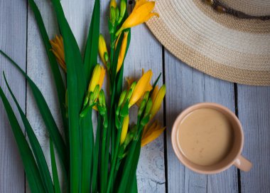 Sarı lilyum buketi, şapka ve bir fincan kahve ahşap bir masaya Servis Kahvaltı