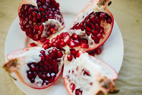 Cutted Red Ripe Pomegranates White Plate Craft Paper Background — Stock Photo, Image