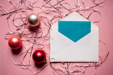 Noel kompozisyon. Zarf bir kart ile. Noel süslemeleri pembe bir arka plan üzerinde kırmızı ve pembe.