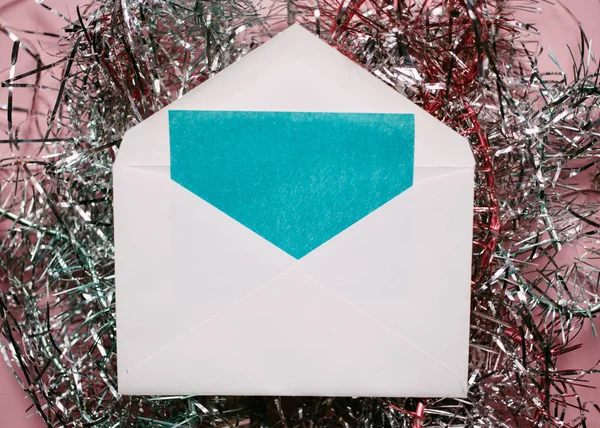 Christmas composition. Envelope with a card. tinsel decorations on pink background.