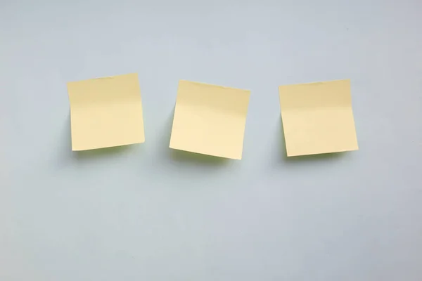 Three yellow paper stickers note with copy space on light blue background