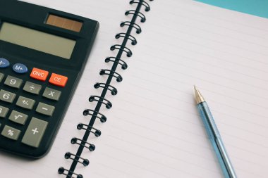 Defter, kalem ve mavi bir arka plan üzerinde bir hesap makinesi