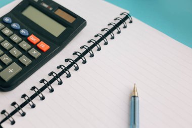 Defter, kalem ve mavi bir arka plan üzerinde bir hesap makinesi