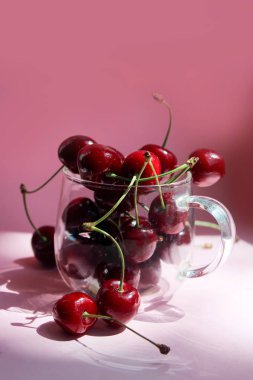 Şeffaf kasede kiraz, pembe arka plan. Kırmızı kiraz. Taze kiraz. sağlıklı gıda kavramı