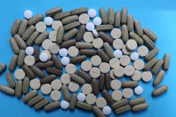 Pillole, compresse e capsule di medicinali assortiti su sfondo blu Immagini Stock Royalty Free