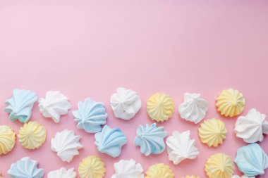 Kopya alanı ile pembe pastel arka plan üzerinde çok renkli beze. Lezzetli tatlı. Renkli el yapımı beze.