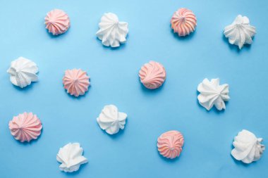 Mavi pastel arka plan üzerinde çok renkli beze. Lezzetli tatlı. Renkli el yapımı beze.