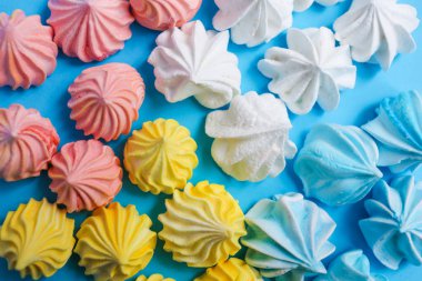 Mavi pastel arka plan üzerinde çok renkli beze. Lezzetli tatlı. Renkli el yapımı beze.