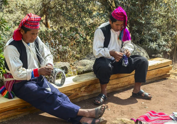 Taquile insel, titicacasee, peru - 04. september 2019 - zwei ältere eingeborene männer der taquile insel stricken einen traditionellen hut. auf der taquile insel stricken die männer und die frauen weben. — Stockfoto