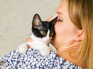 Sevimli bir kediyi kucaklayan, okşayan ve öpen sıradan giyinmiş bir kadının hayat tarzı fotoğrafı. Kedi, kızların kollarında olmaktan hoşlanıyor. Seçici odak.