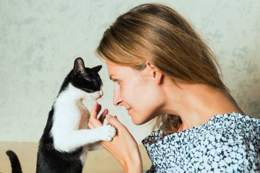 Sevimli bir kediyi kucaklayan, okşayan ve öpen sıradan giyinmiş bir kadının hayat tarzı fotoğrafı. Kedi, kızların kollarında olmaktan hoşlanıyor. Seçici odak.