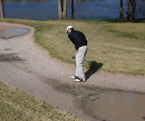 Golfer schlägt aus einer überfluteten Sandfalle auf einem schlecht gewarteten — Stockfoto