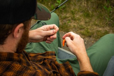 Balıkçı bir kanca üzerinde sahte bir solucan Baiting