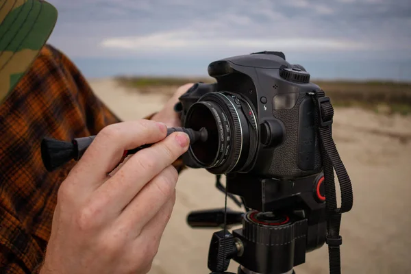 Fotografo che pulisce le lenti della fotocamera su un treppiede — Foto Stock