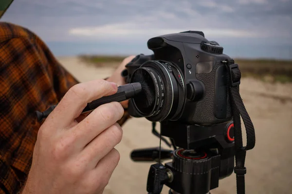 Fotografo che pulisce le lenti della fotocamera su un treppiede — Foto Stock