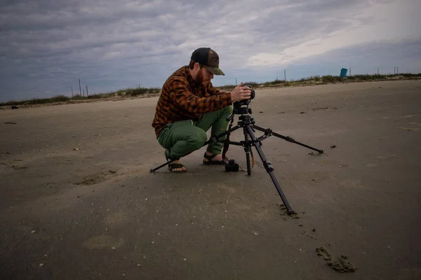 Fotógrafo de playa agachado usando un trípode —  Fotos de Stock