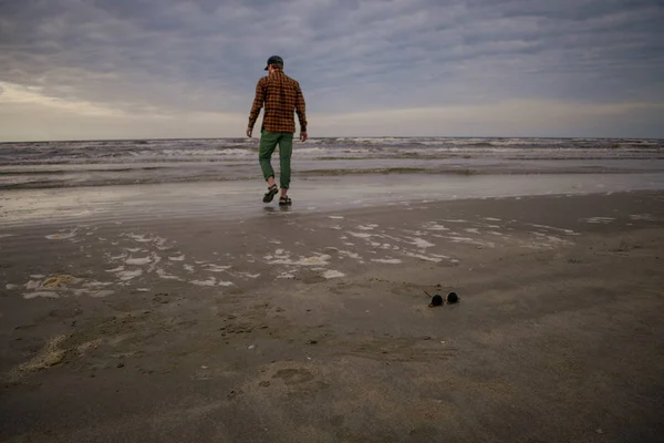 Trendy model op het strand wandelen in het water volledig gekleed — Stockfoto