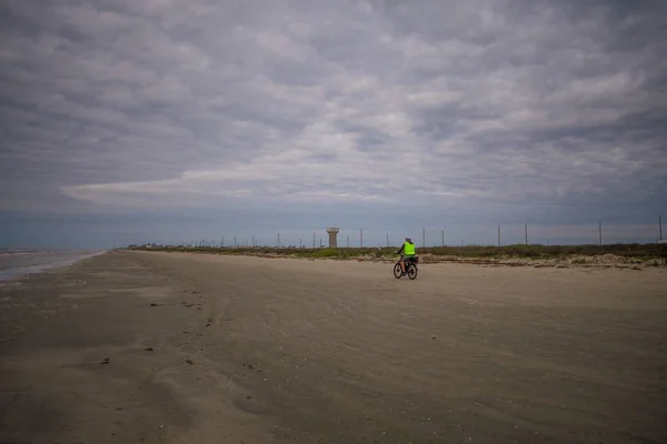 Άνθρωπος ιππασίας ποδήλατο στην παραλία υπό θυελλώδεις συνθήκες — Φωτογραφία Αρχείου