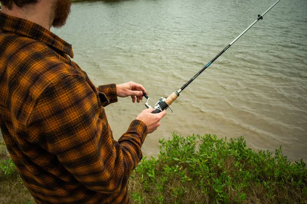 Fiskare i aktion med Reel i förgrunden reeling i Fish — Stockfoto