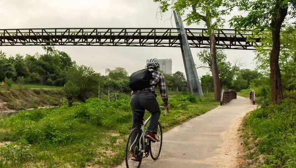 Man Biking To Work Under City Bridge