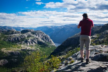 Turist, Stavanger Norveç 'teki uçuruma giderken fiyordun fotoğrafını çekiyor.