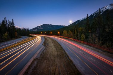 Alberta Rocky Dağları üzerinden Trans-Kanada karayolu üzerinde kırmızı ve beyaz araba hafif yollarının uzun pozlama fotoğraf