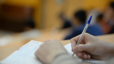Öğrenciler sınıfta (okul) Üniversitesi'nde. Defterler, kalemler, eller yukarı yakın.