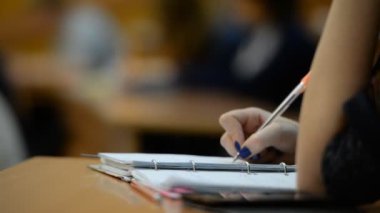 Öğrenciler sınıfta (okul) Üniversitesi'nde. Defterler, kalemler, eller yukarı yakın.