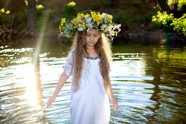美丽的女孩在白色礼服在花圈散步在水上 — 图库照片