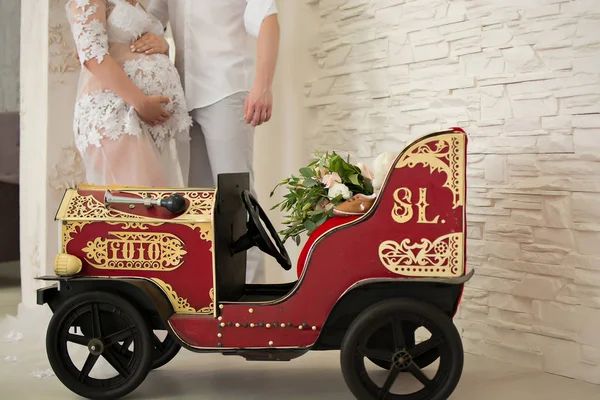 美丽的怀孕夫妇和一辆玩具车与花束 — 图库照片