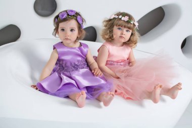 Beyaz bir odada elbise giymiş güzel çocuklar. Kızlar oynar ve güler.