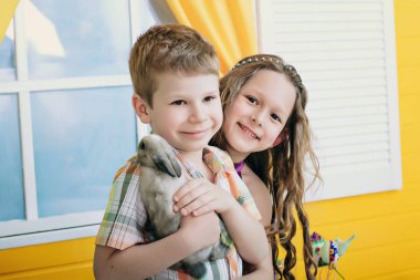 Mutlu çocuk bir tavşan ile oyun. bir erkek ve bir kız bir parlak Oda kahkaha ve oyun