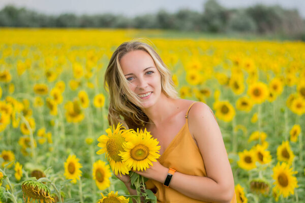 Happy woman with sunflowers. The girl in the fields of a sunflower