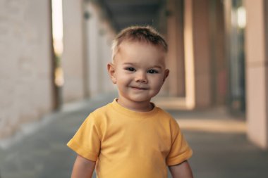 Küçük bir çocuk şehirde yürüyüş. Kentsel tarzı ve çocuk. Sarı tişört çocukta