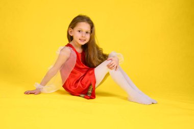 Çocuk sınıf gösterir ve bölmeleri üzerinde oturur. Sarı arka plan. Stilize kırmızı elbiseli uzun saçlı kız