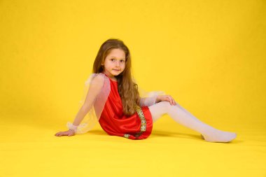 Çocuk sınıf gösterir ve bölmeleri üzerinde oturur. Sarı arka plan. Stilize kırmızı elbiseli uzun saçlı kız