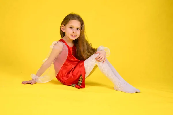 Çocuk sınıf gösterir ve bölmeleri üzerinde oturur. Sarı arka plan. Stilize kırmızı elbiseli uzun saçlı kız