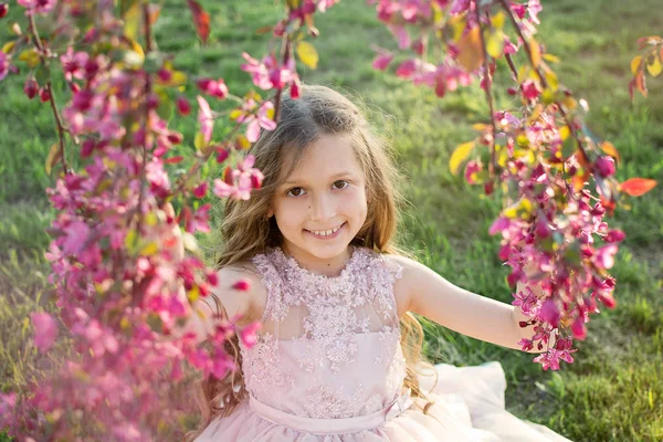 一个漂亮的婴儿在微笑 女孩金发在开花的树木 大自然中儿童的肖像 — 图库照片