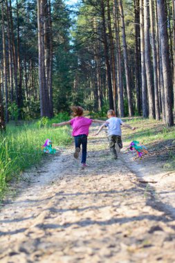 Bir erkek ve bir kız ormanda oynuyorlar. Çocuklar uçurtma uçuruyor