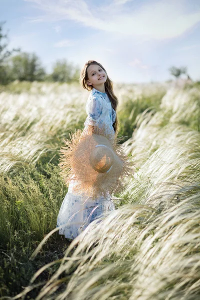野原の麦わら帽子をかぶった少女長い髪の少女は夏に野原を歩く 赤ちゃんの笑顔 — ストック写真