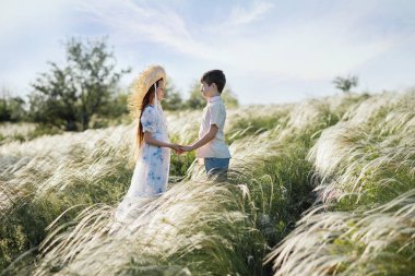 Tarlalarda bir kız ve bir kız oynuyorlar. Hasır şapkalı çocuklar. İki çocuğun yolculuğu