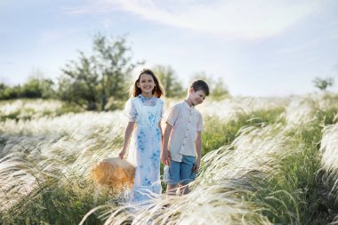 Tarlalarda bir kız ve bir kız oynuyorlar. Hasır şapkalı çocuklar. İki çocuğun yolculuğu