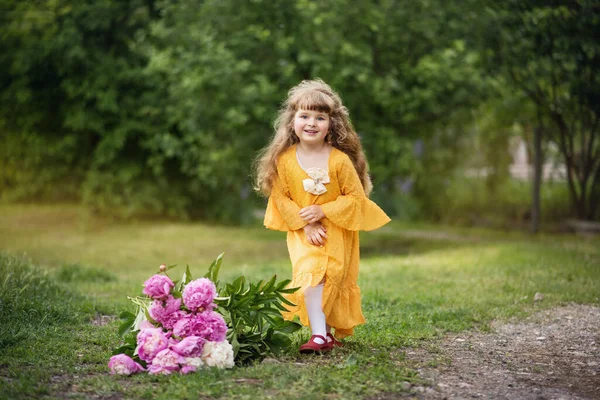 小女孩在公园里玩 那孩子在走路 暑假休息 长长的金发碧眼的微笑 美丽的婴儿和牡丹 带着一束花的女孩 — 图库照片