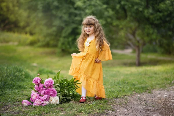 小さな女の子が公園で遊んでいる 子供は歩いている 夏休みだ 長い髪のブロンドの笑顔 牡丹の美しい赤ちゃん 花の花束を持つ女の子 — ストック写真